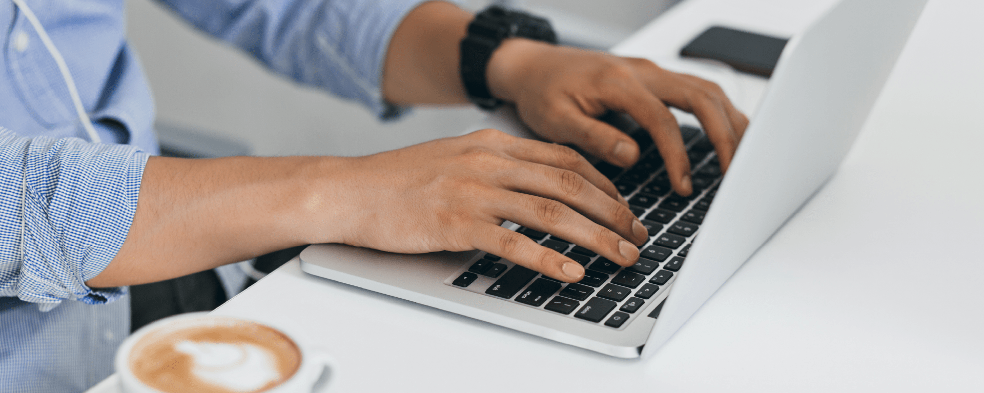 Man using a laptop zoomed in on his hands on the keyboard